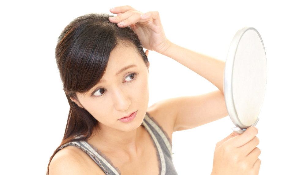 A sad woman with Hair-Pulling Disorder looking at her hair in the mirror.